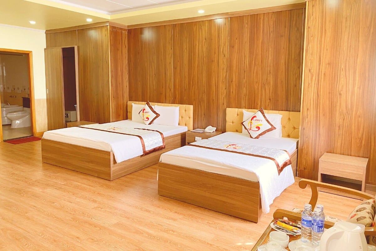 A hotel room with two wooden beds, a small table with breakfast items, and a wooden floor.