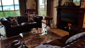A cozy living room with a leather sofa, a glass coffee table, and a fireplace. - Waterview Gardens B&B (Margate)
