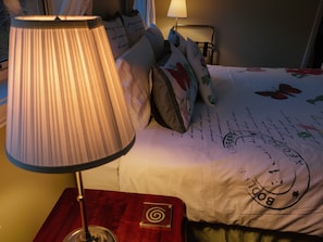 A bed with a floral comforter, a lamp on a bedside table, and a wall-mounted nightstand. - Waterview Gardens B&B (Margate)