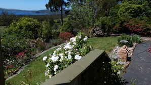 A garden with various plants and flowers, a pathway, and a view of the sea. - Waterview Gardens B&B (Margate)