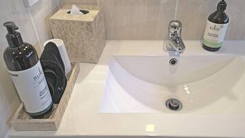 A bathroom sink with a tissue box, a bottle of hand soap, and a bottle of body wash.