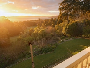 A view of a landscaped garden with a wooden post and a metal water bottle, overlooking a grassy area and trees. - Waterview Gardens B&B (Margate)