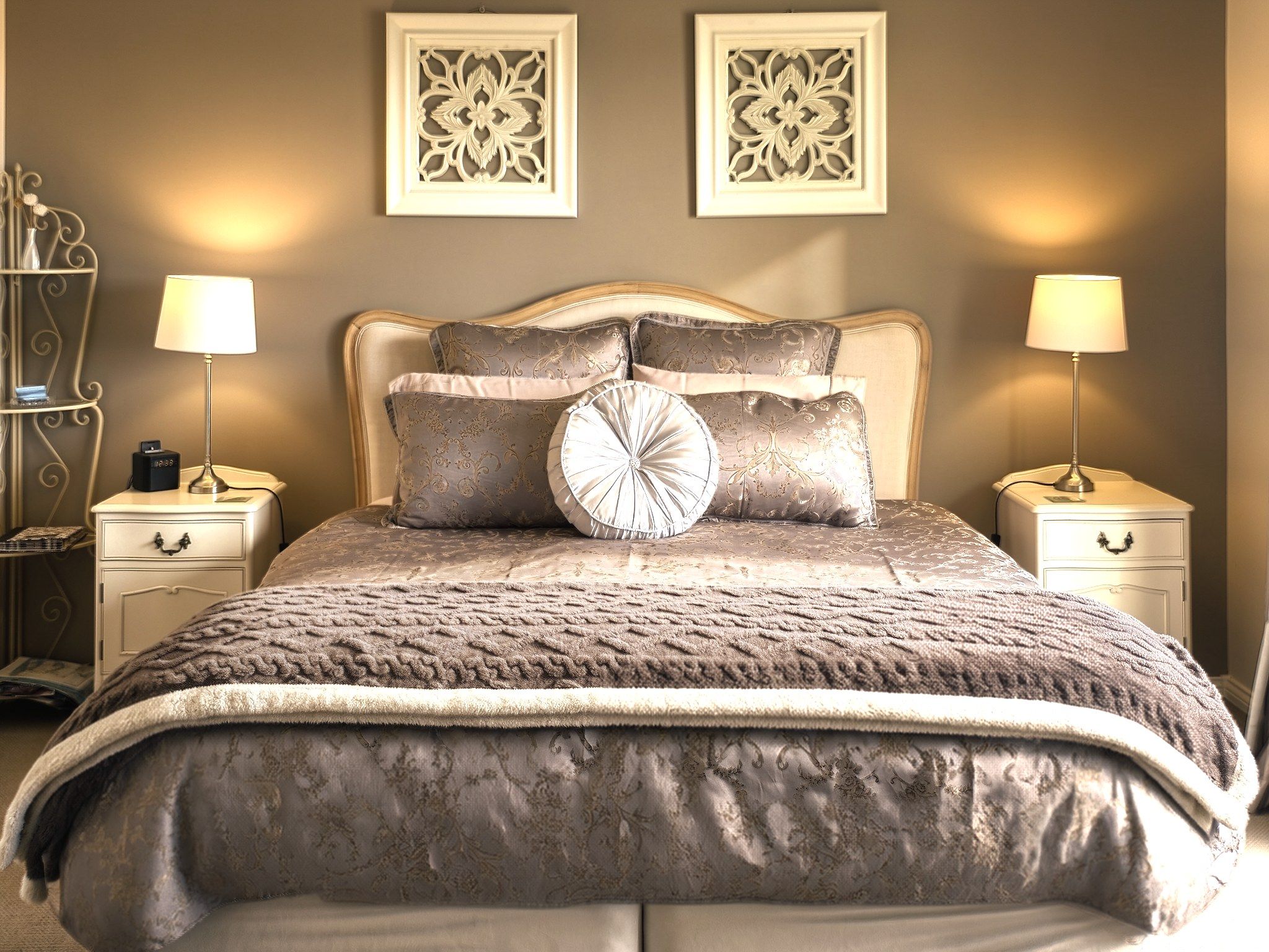 A bed with a textured blanket, two bedside tables with lamps, and decorative wall art.