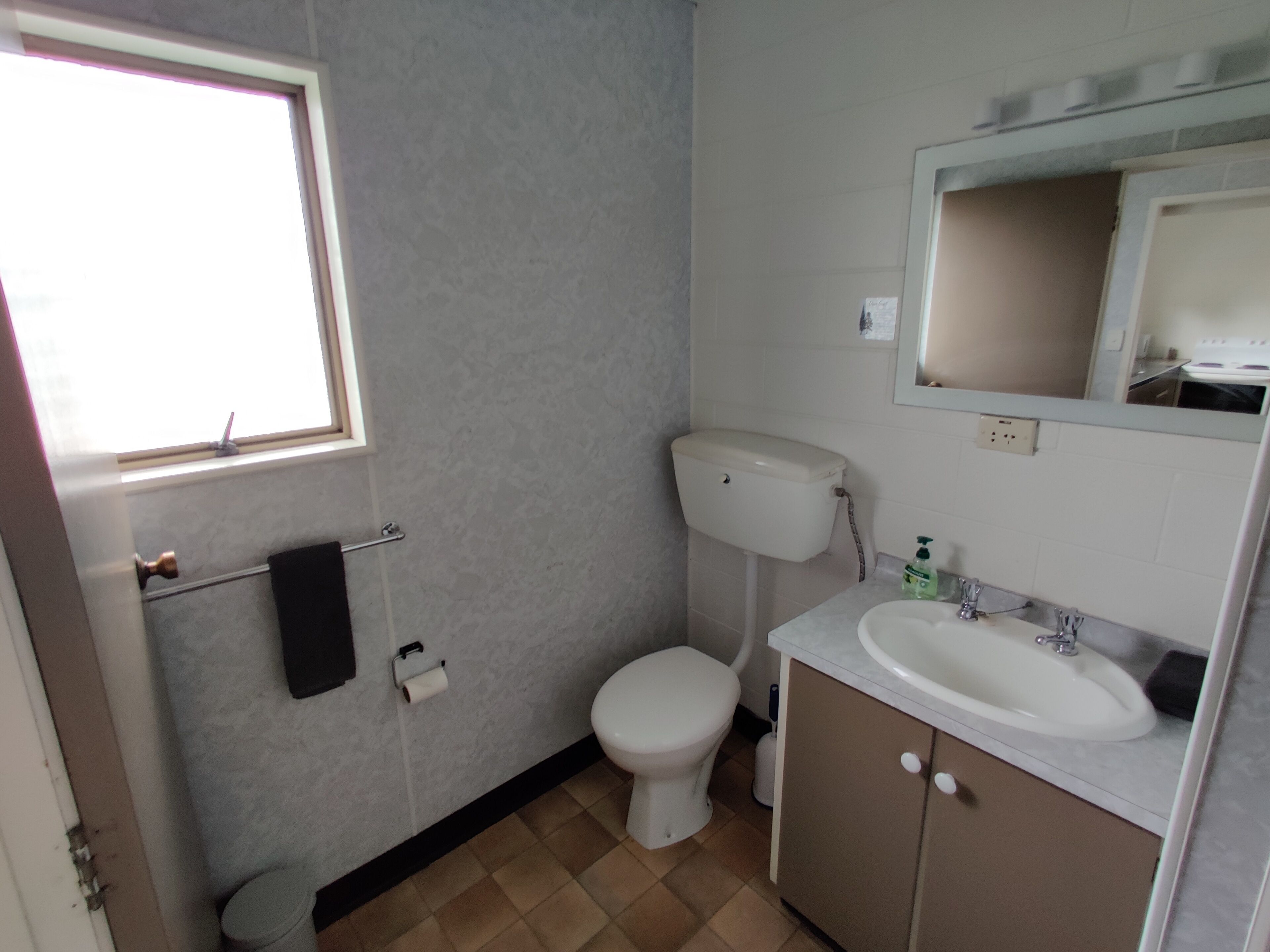 Ein Badezimmer mit Toilette, Waschbecken und Fenster.