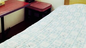 A room with a bed, a desk, a chair, a window, and a wall-mounted air conditioner. - Business Hotel Mayumi (Omuta)