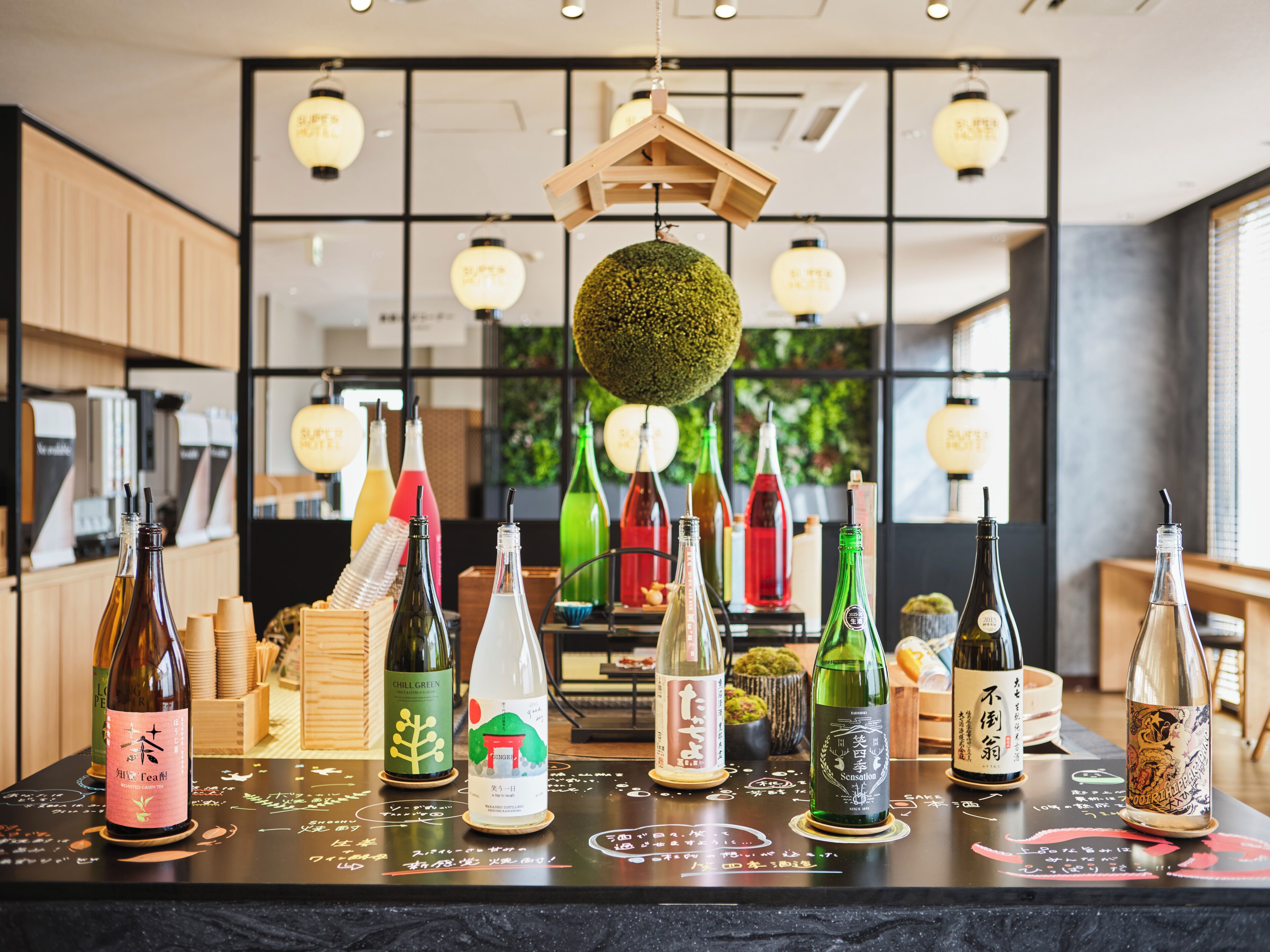 A bar area with various bottles of beverages, a wooden hanging light fixture, and a green decorative sphere.