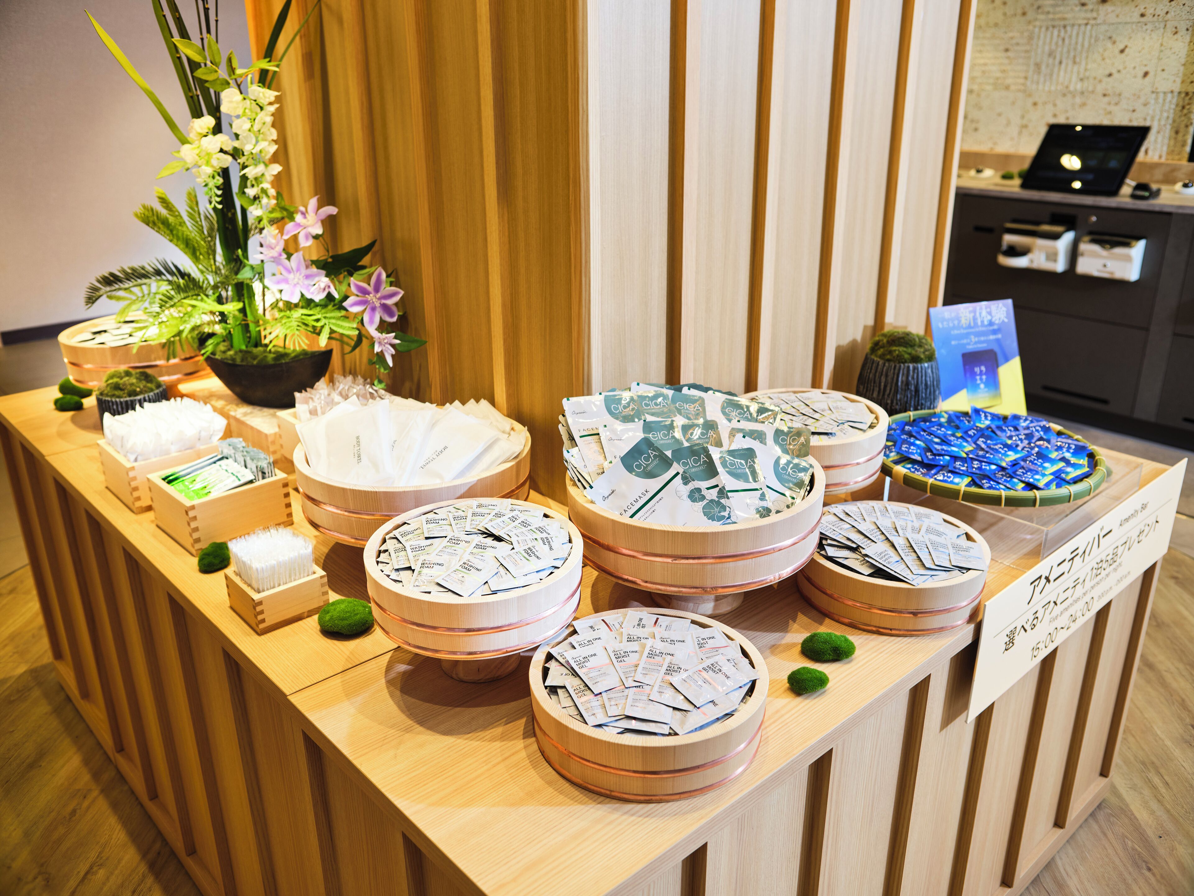 Un comptoir d’accueil agrémenté de divers objets, notamment une plante en pot, un panneau avec du texte en japonais et plusieurs paniers contenant différents articles.
