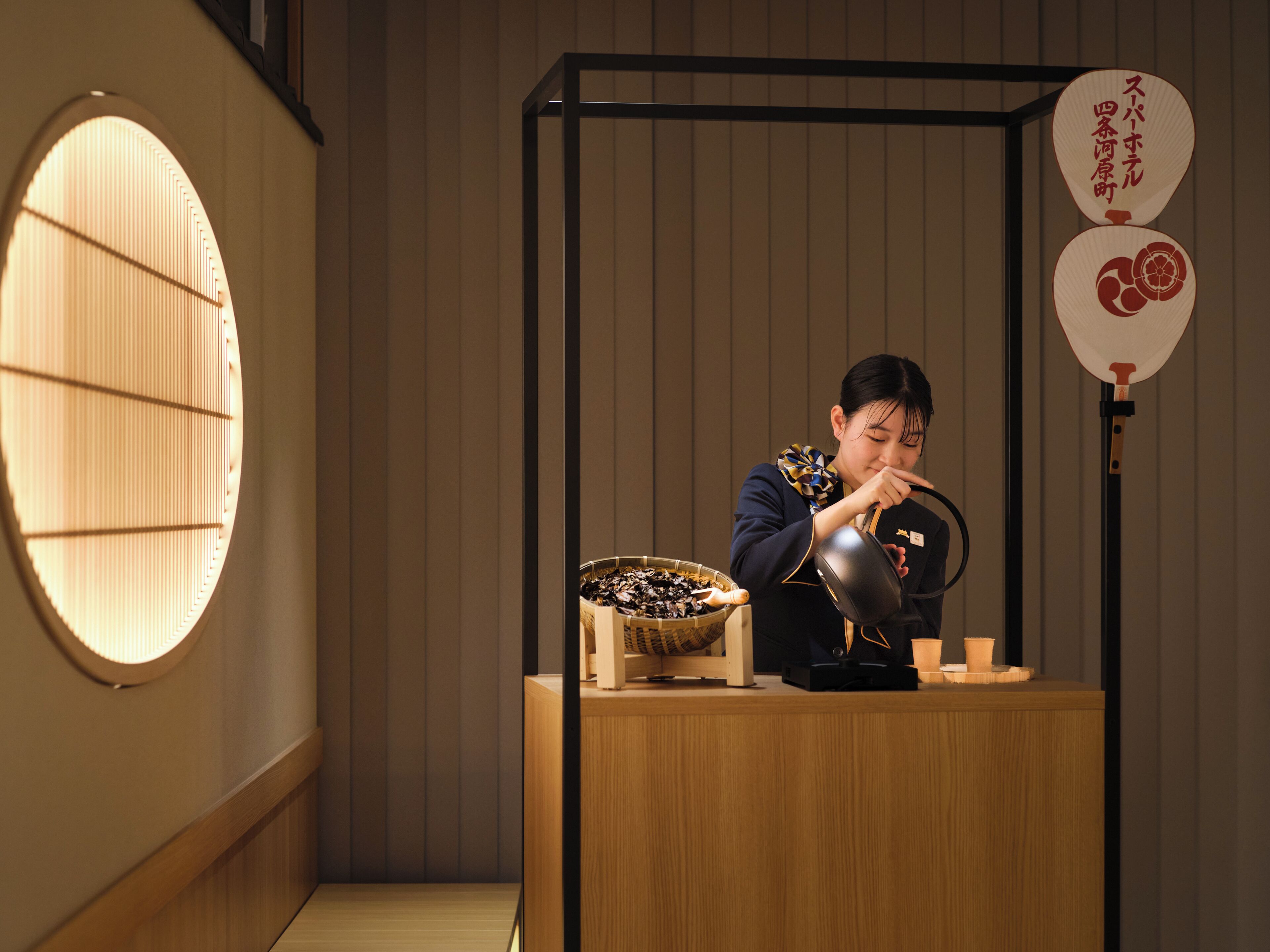 A person at a counter with a bowl of snacks, a fan, and a decorative item.