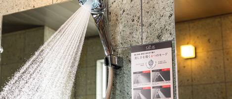 A shower with water spraying down, a sign with Japanese text, and a tiled wall.