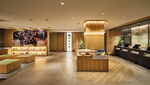 A modern hotel lobby with a reception desk, seating area, and a wall with cultural decorations. - Super Hotel Kyoto Shijyo Kawaramachi (Kyoto)
