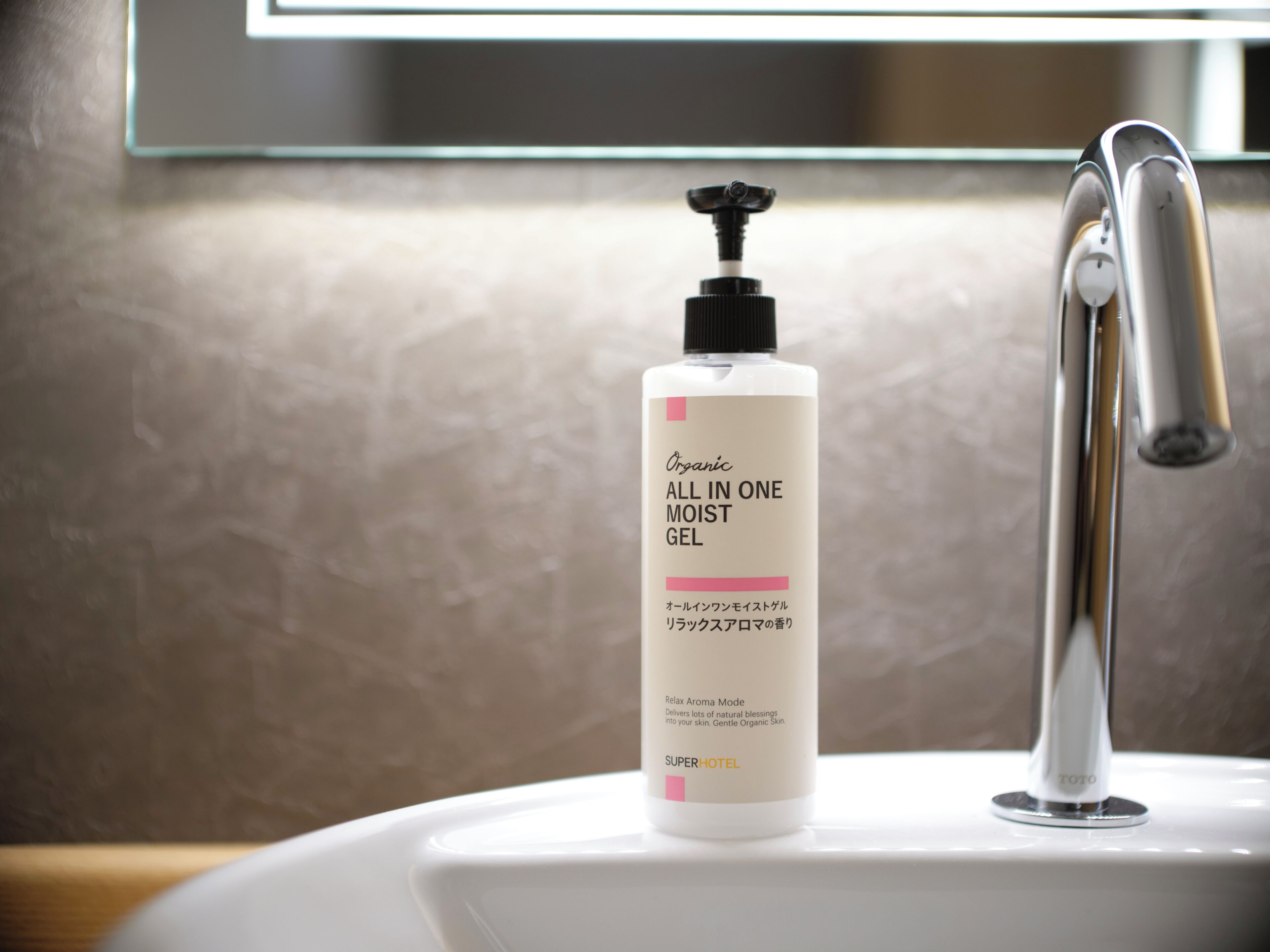 A bathroom sink with a bottle of 'ALL IN ONE MOIST GEL' and a modern faucet.
