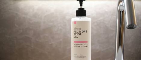 Un lavamanos con una botella de 'ALL IN ONE MOIST GEL' y un grifo moderno.
