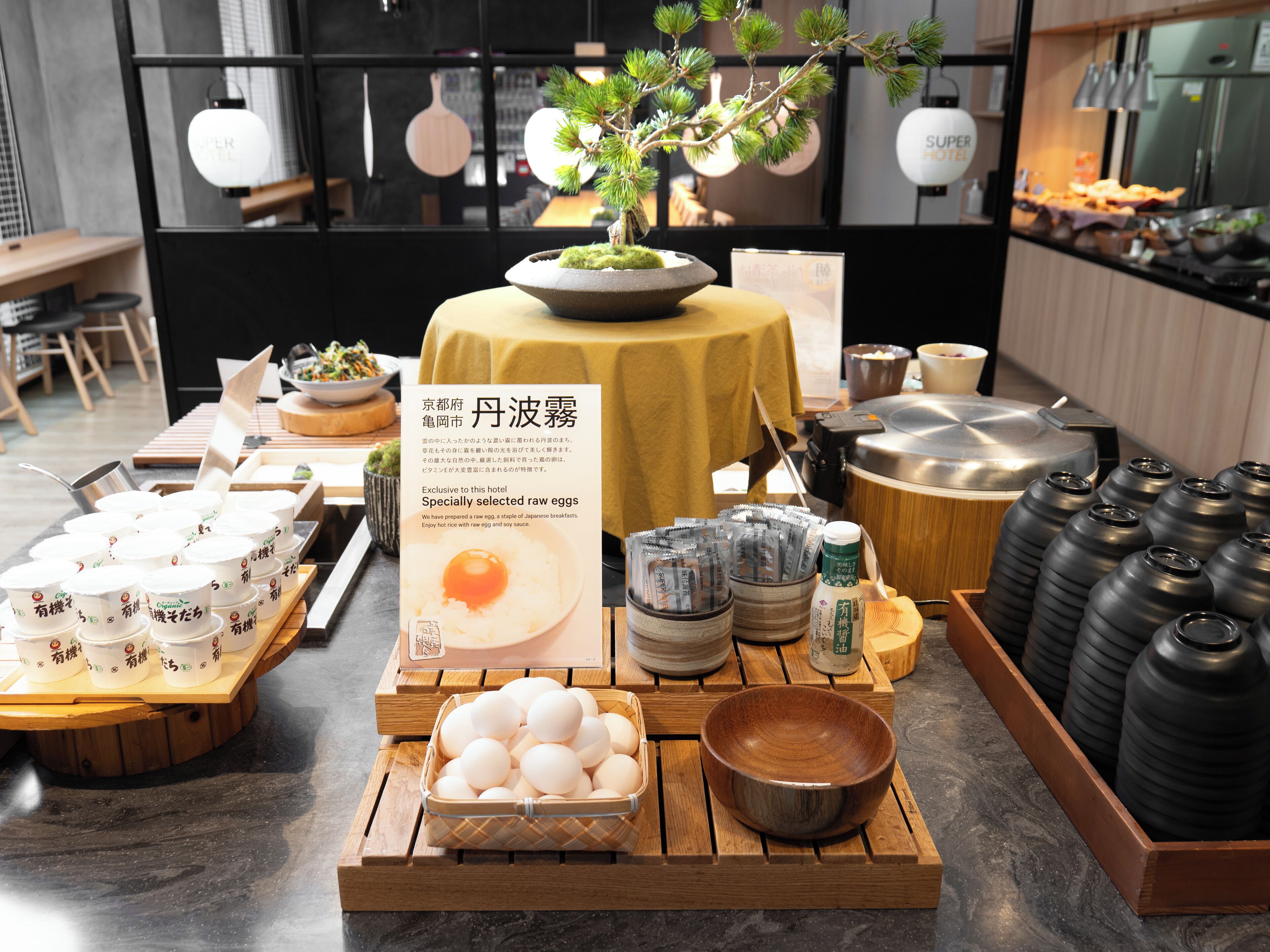 Presentación de alimentos para desayuno japonés, como huevos, salsa de soja y té.