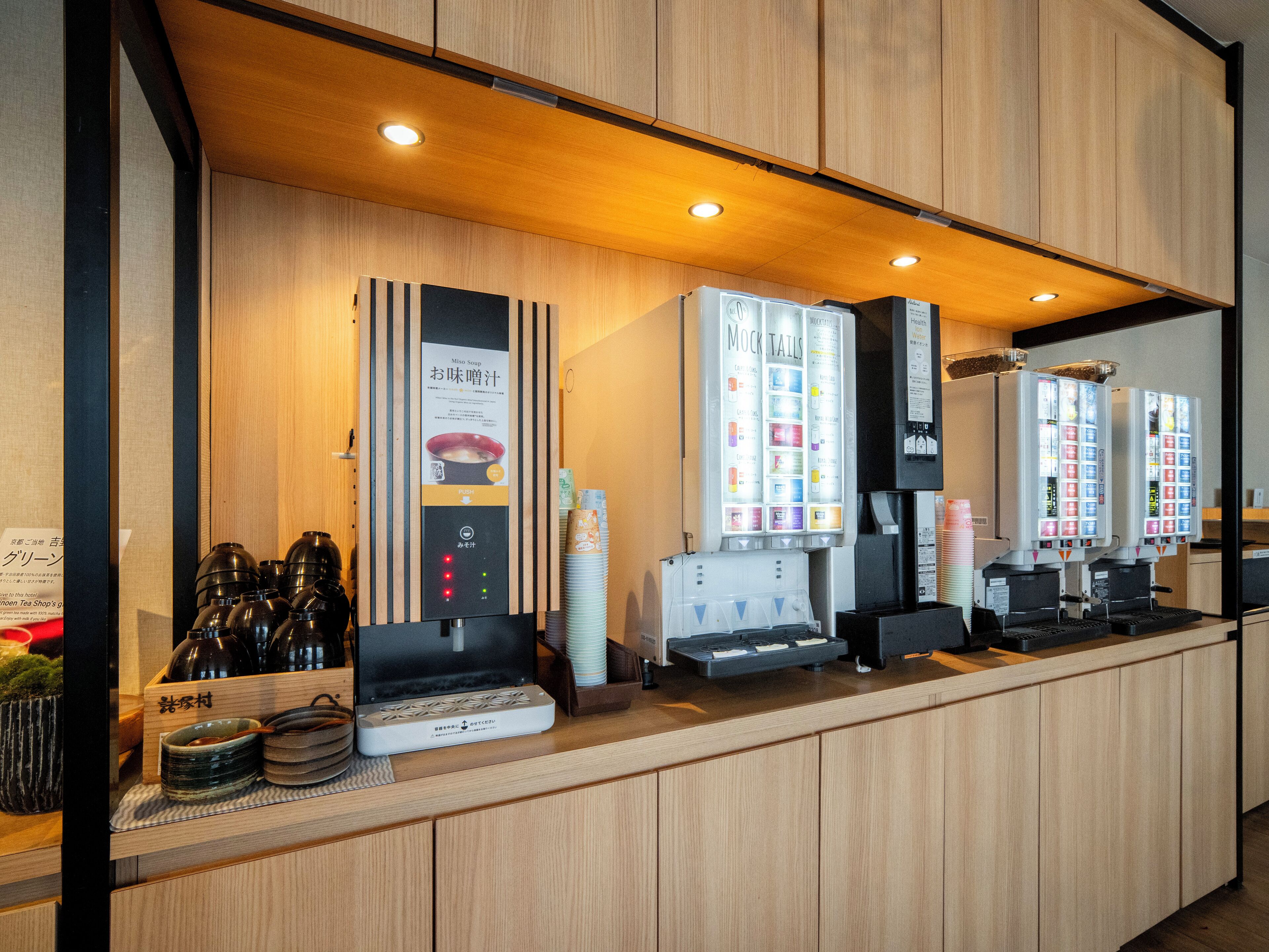 A modern reception area with wooden paneling, a counter with tea and coffee dispensers, and a menu display.
