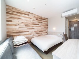 Una moderna camera d'hotel con una parete in legno, un letto, un'area salotto e una scrivania.