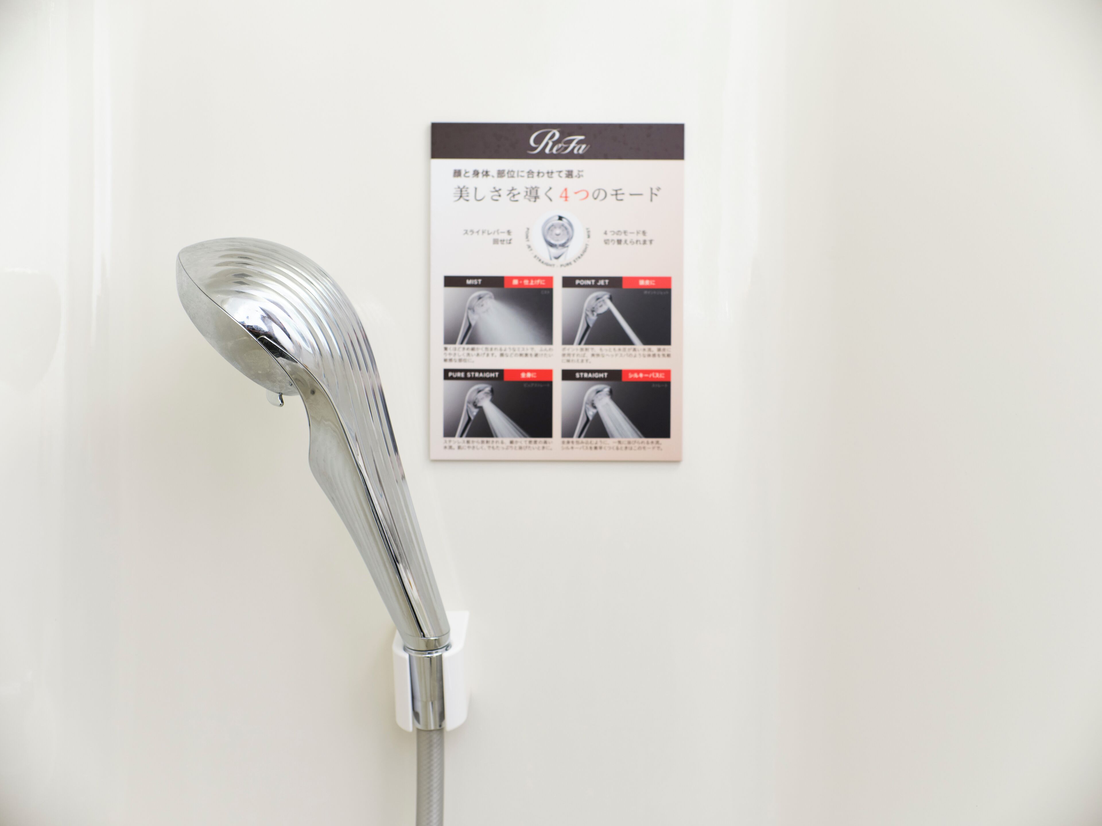 A showerhead mounted on a wall with a sign displaying different showerhead models.