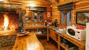 A cozy cabin-style kitchen with a wood-burning stove, wooden countertops, and basic appliances. - Riverside Lodge (Oudtshoorn)