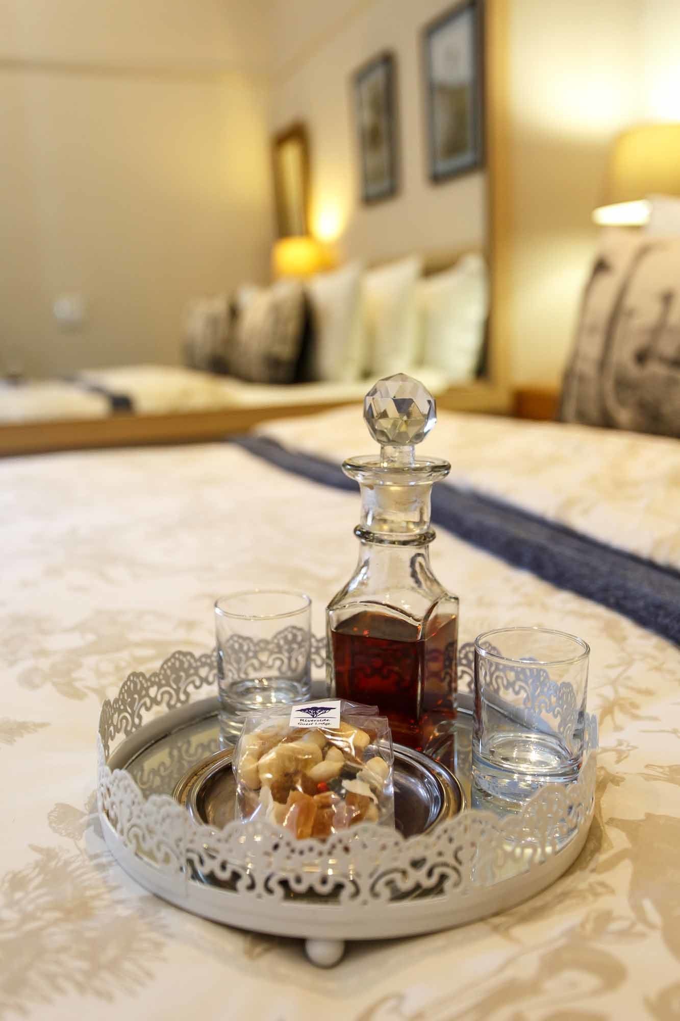 A tray with a decanter, two glasses, and a bowl of nuts on a table.