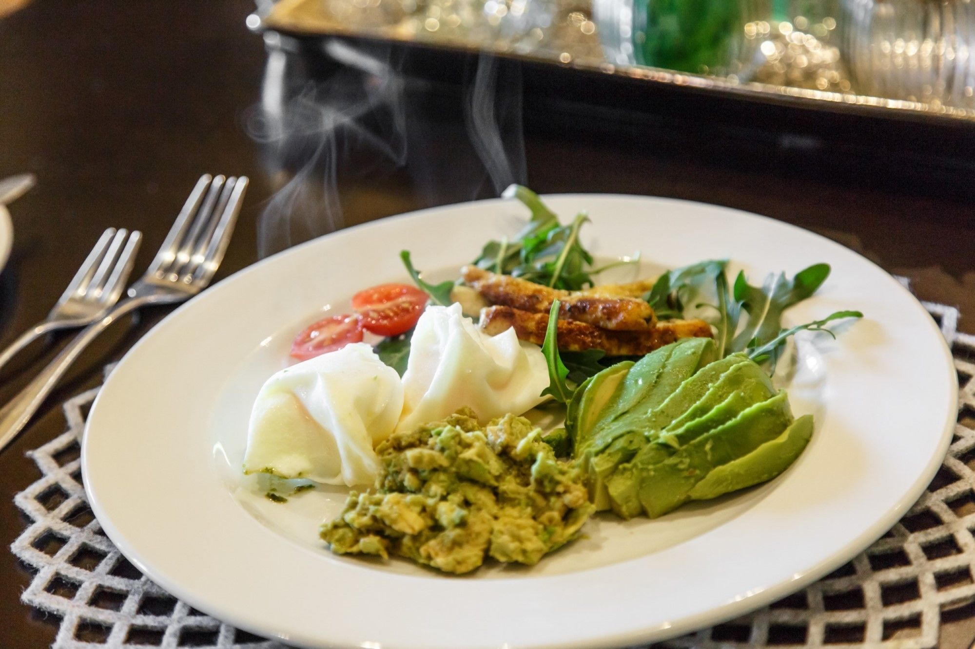 Une assiette blanche contenant une salade, un œuf poché et une tranche d’avocat.