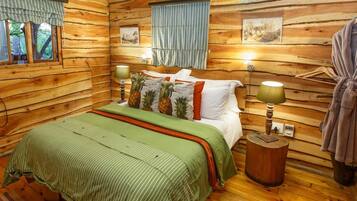 A cozy log cabin bedroom with a bed, pillows, a nightstand, and a lamp.