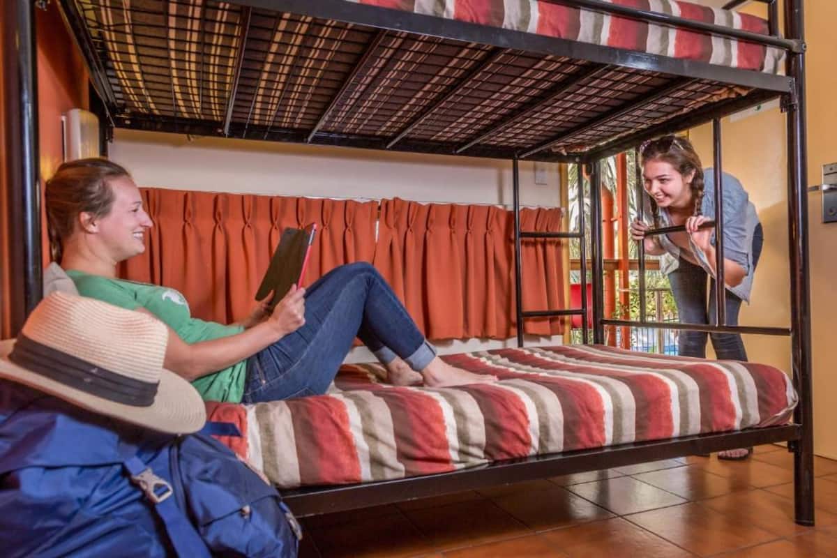 A bunk bed room with two people, one sitting and one standing.