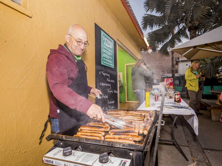 A man grilling sausages on an outdoor grill.