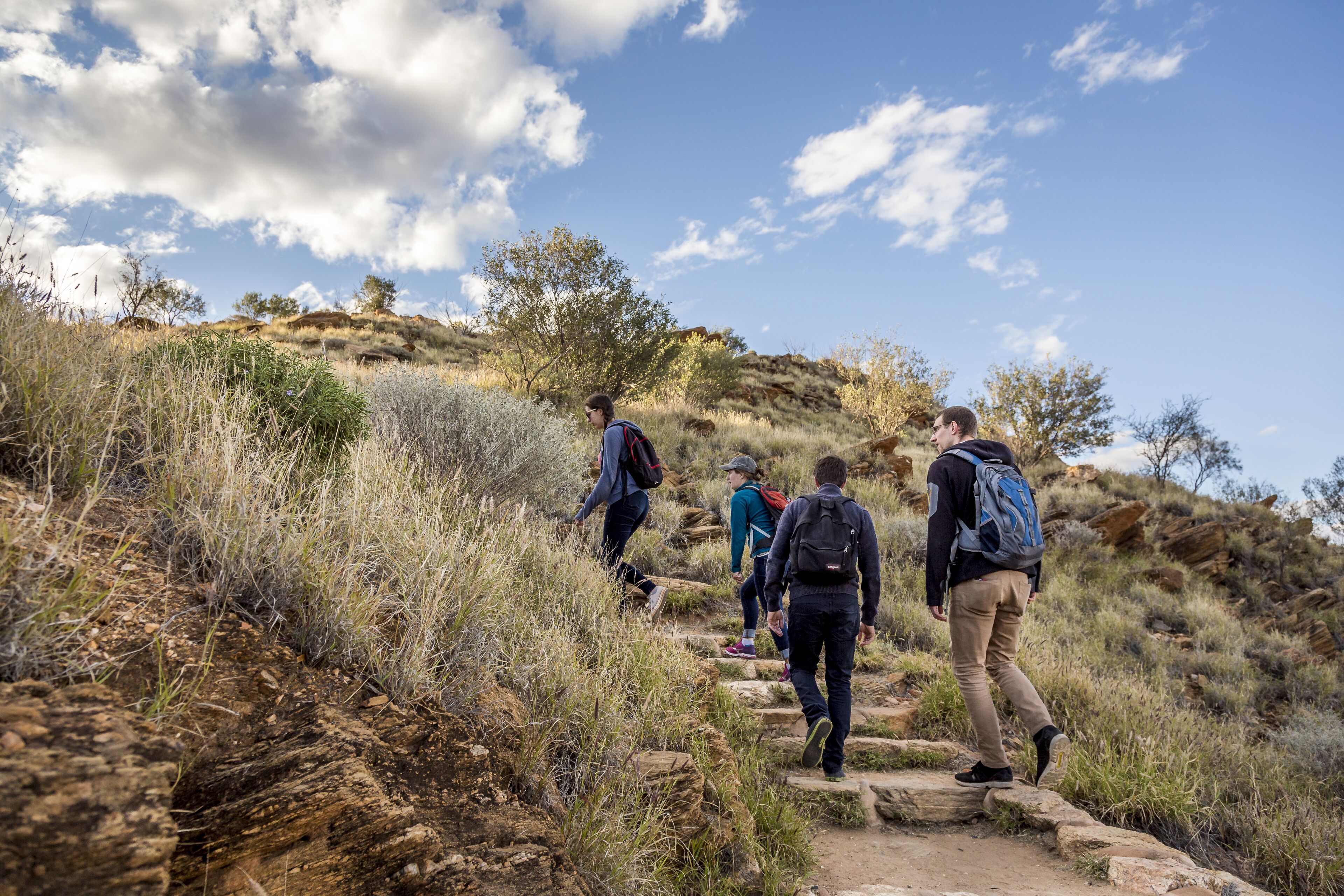 A group of hikers ascending a rocky trail in a natural setting.