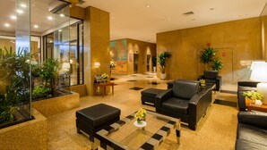 Eine Lobby mit Glaswand, schwarzen Ledersofas, einem Couchtisch und Topfpflanzen.