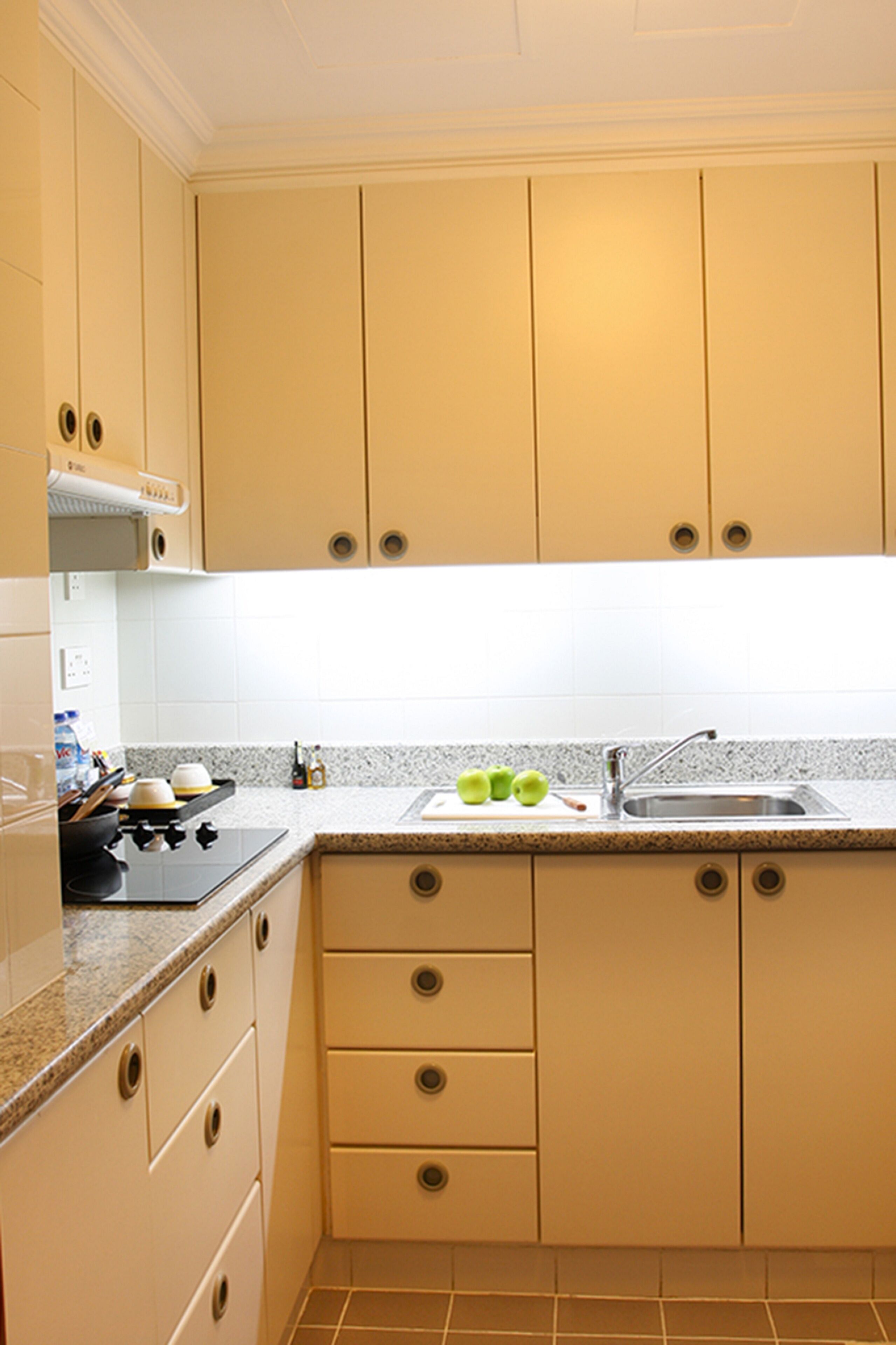 A kitchen with beige cabinets, a granite countertop, a sink, and a stove.