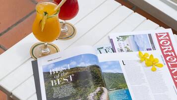 A magazine open on a white table with drinks and a flower decoration.