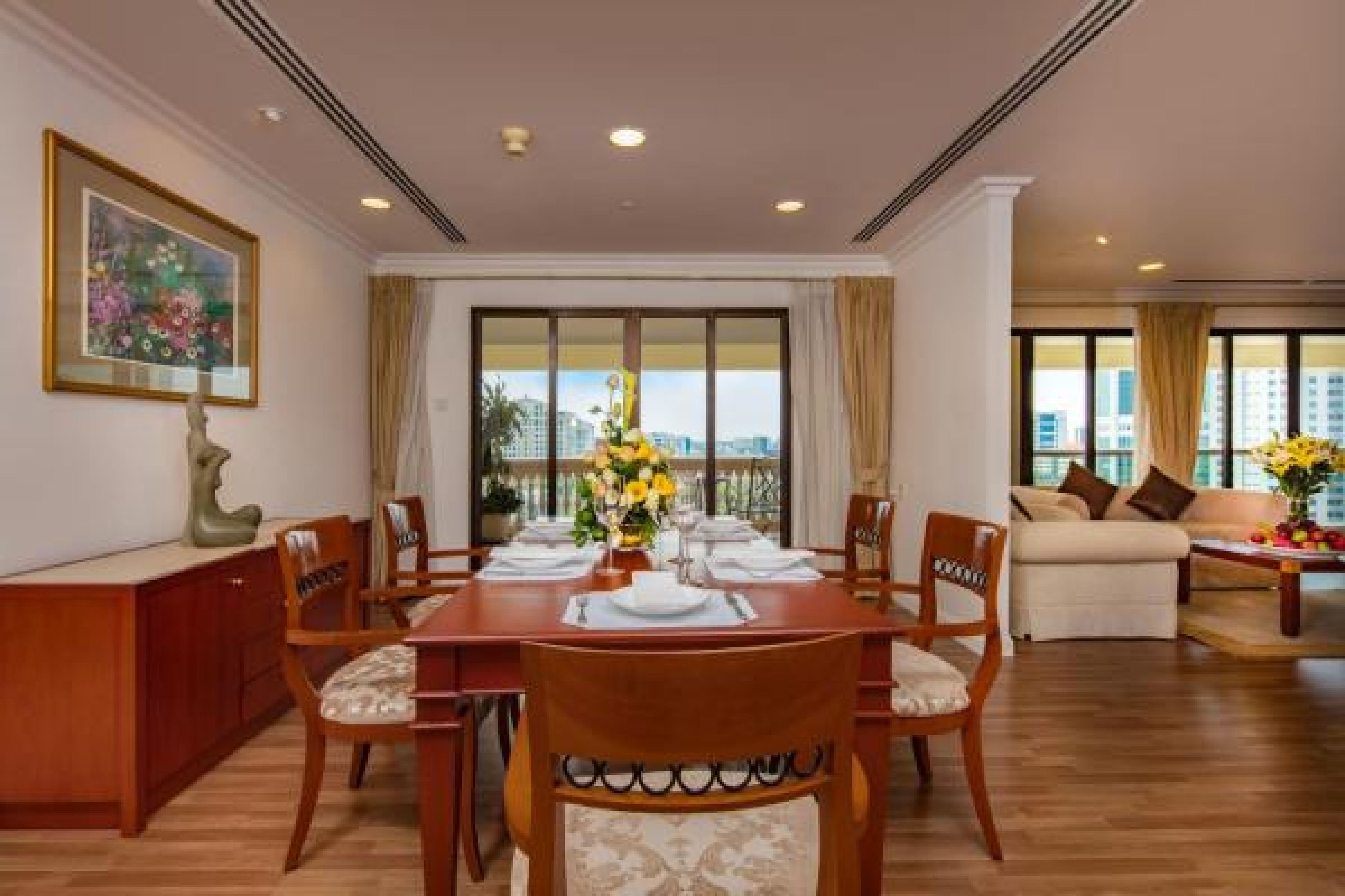 A dining area with a wooden table set for six, surrounded by chairs with cushioned seats.