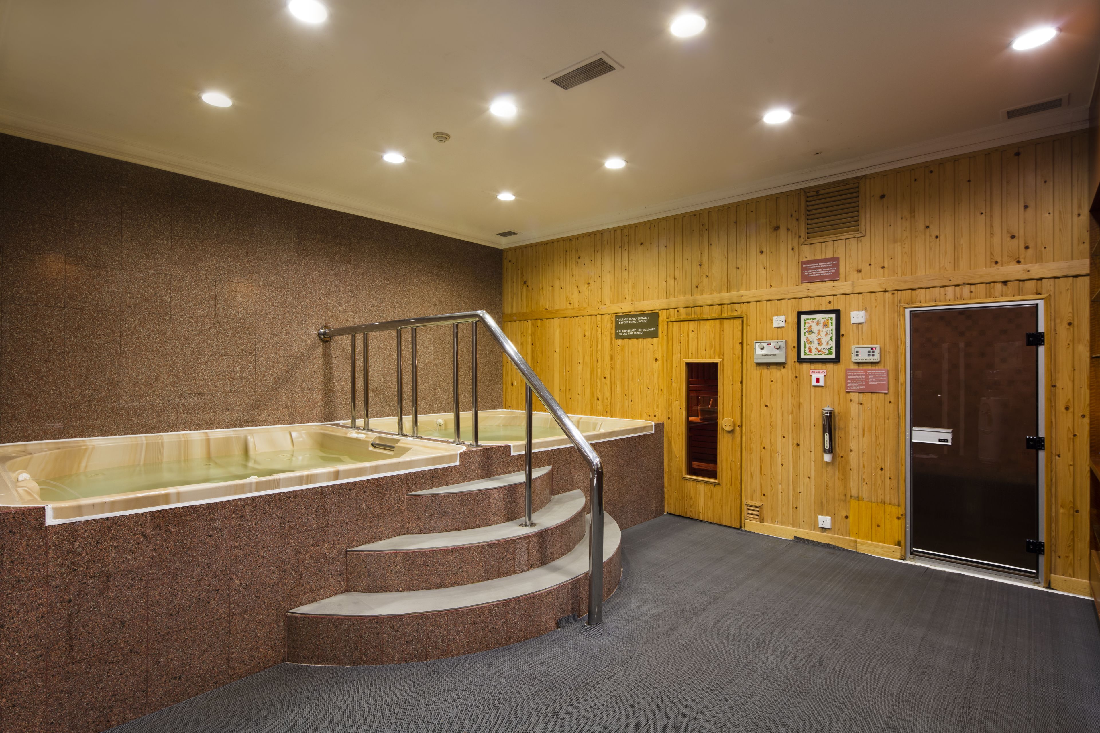 Ein Wellnessbereich mit Whirlpool, einer Treppe und Holzvertäfelung.