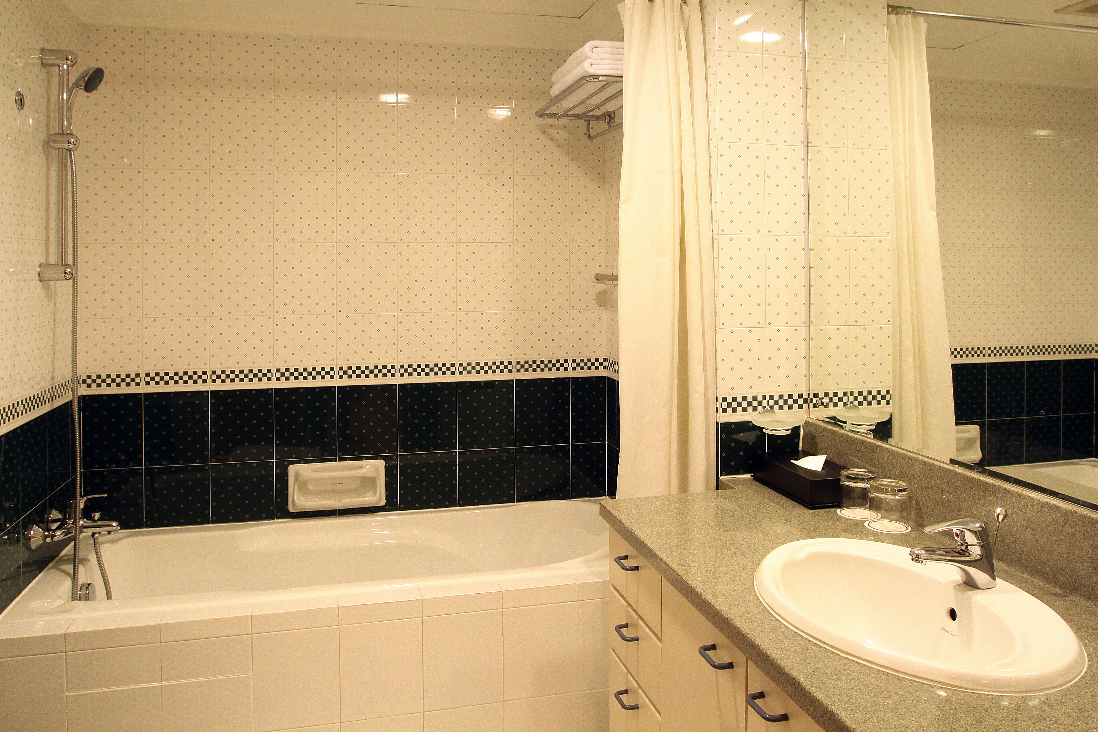 A bathroom with a bathtub, a sink, and a mirror.