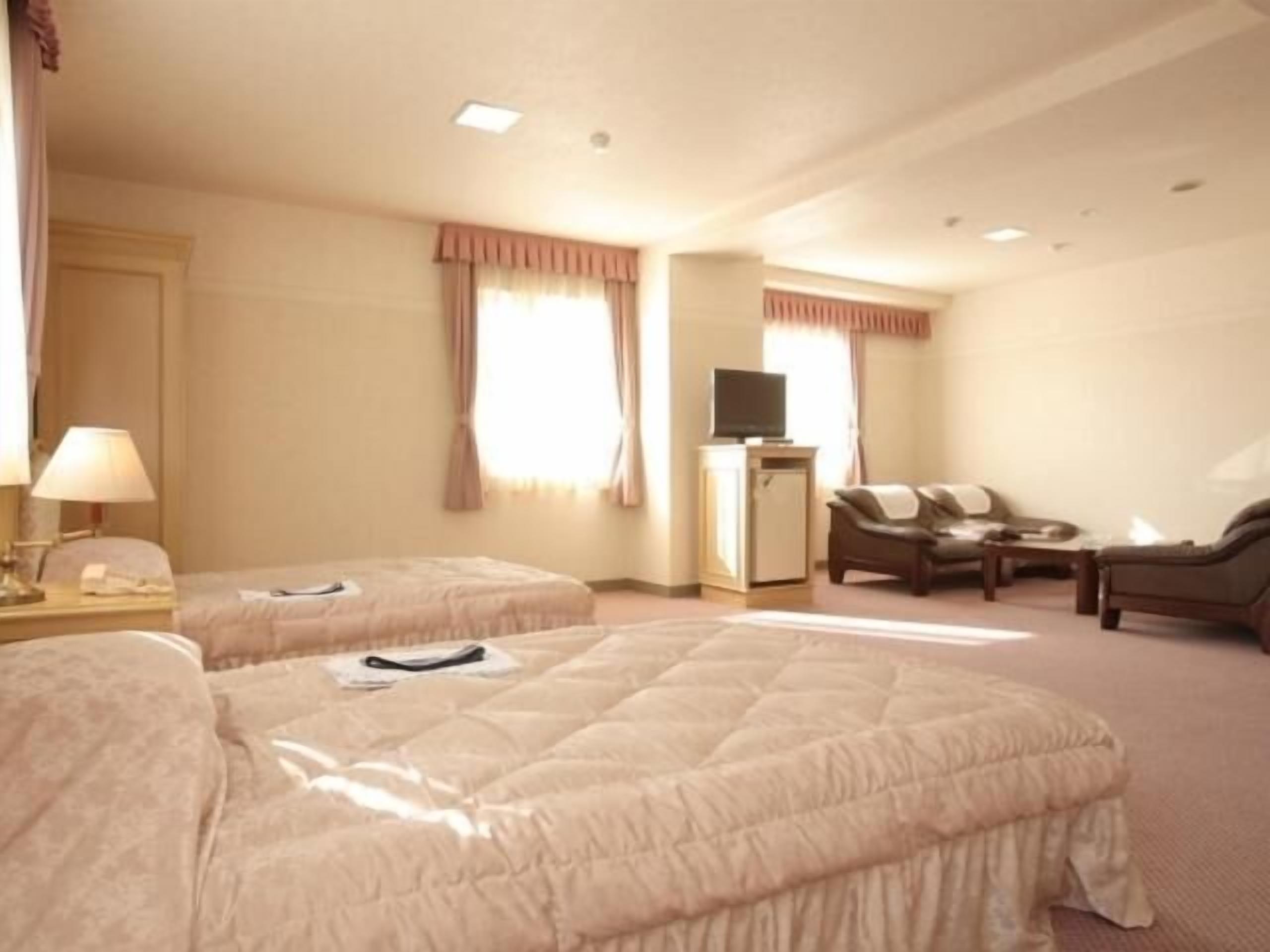 Habitación de hotel con dos camas, un televisor, un sofá y una mesita.