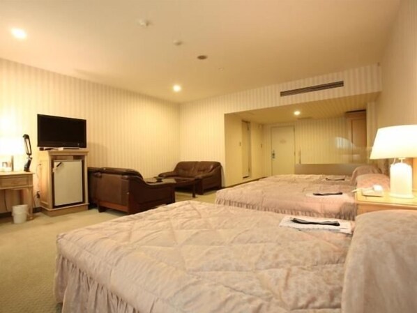 A hotel room with two beds, a desk with a television, a chair, and a mirror. - Nogami President Hotel (Iizuka)