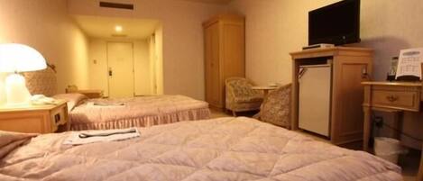 A hotel room with two beds, a television, a desk, and a chair.
