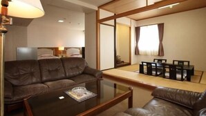 A modern hotel room with a leather sofa, a glass coffee table, and a traditional Japanese sliding door. - Nogami President Hotel (Iizuka)