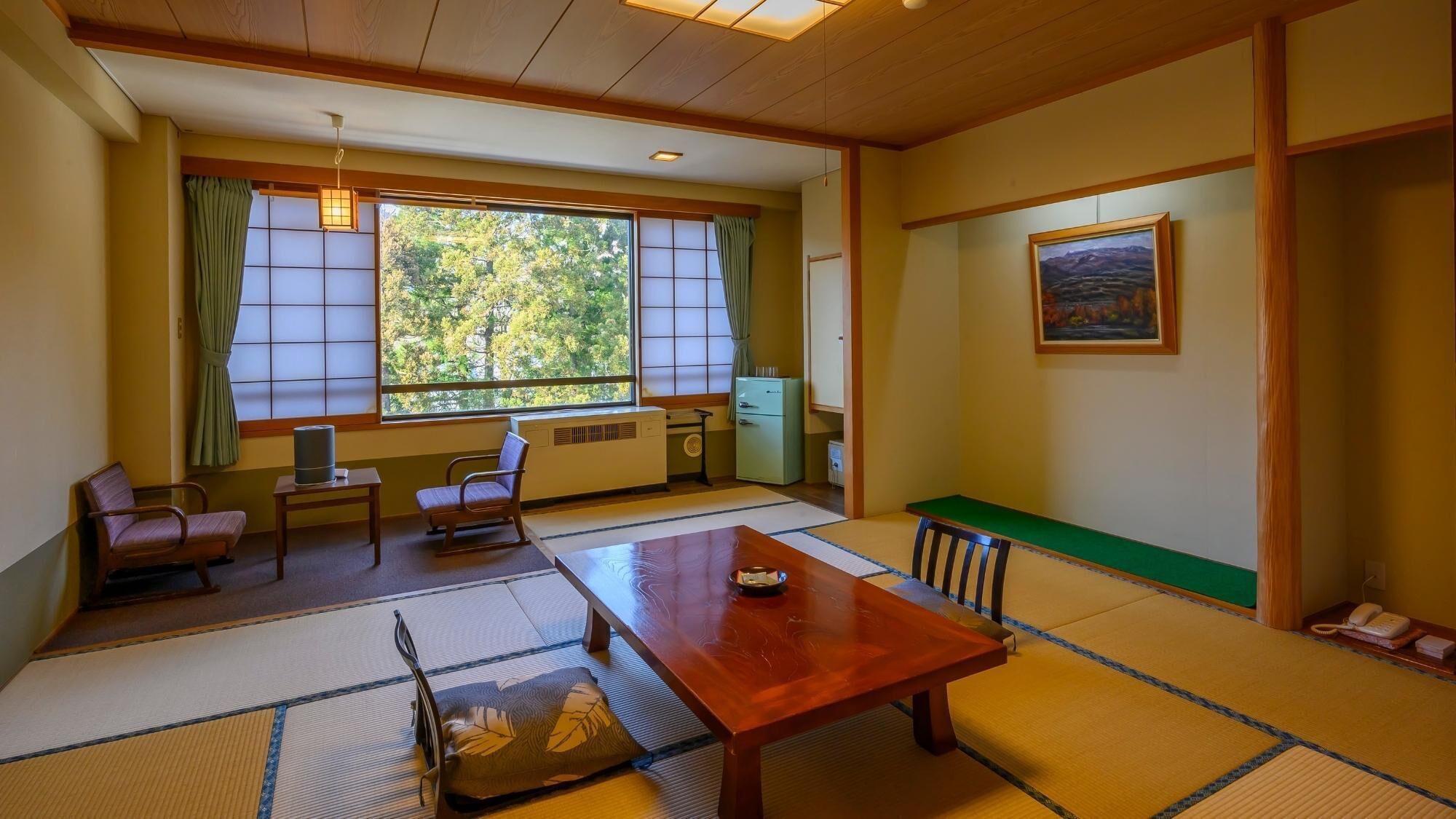 A traditional Japanese-style room with tatami flooring, a low table, chairs, a radiator, and a painting on the wall.