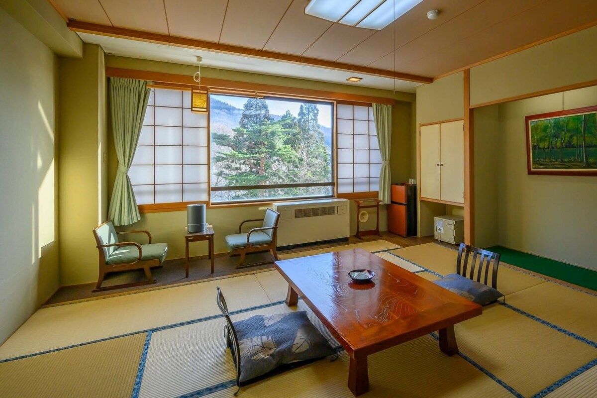 Una habitación japonesa tradicional con suelo de tatami, una mesa baja y puertas correderas.