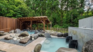 A hot spring area with a wooden structure, rocks, and a pool. - Sakaiya Mori no Hotel Wald Berg (YAMAGATA)