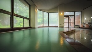 A large indoor swimming pool with clear glass walls, a tiled floor, and a wooden deck area. - Sakaiya Mori no Hotel Wald Berg (YAMAGATA)