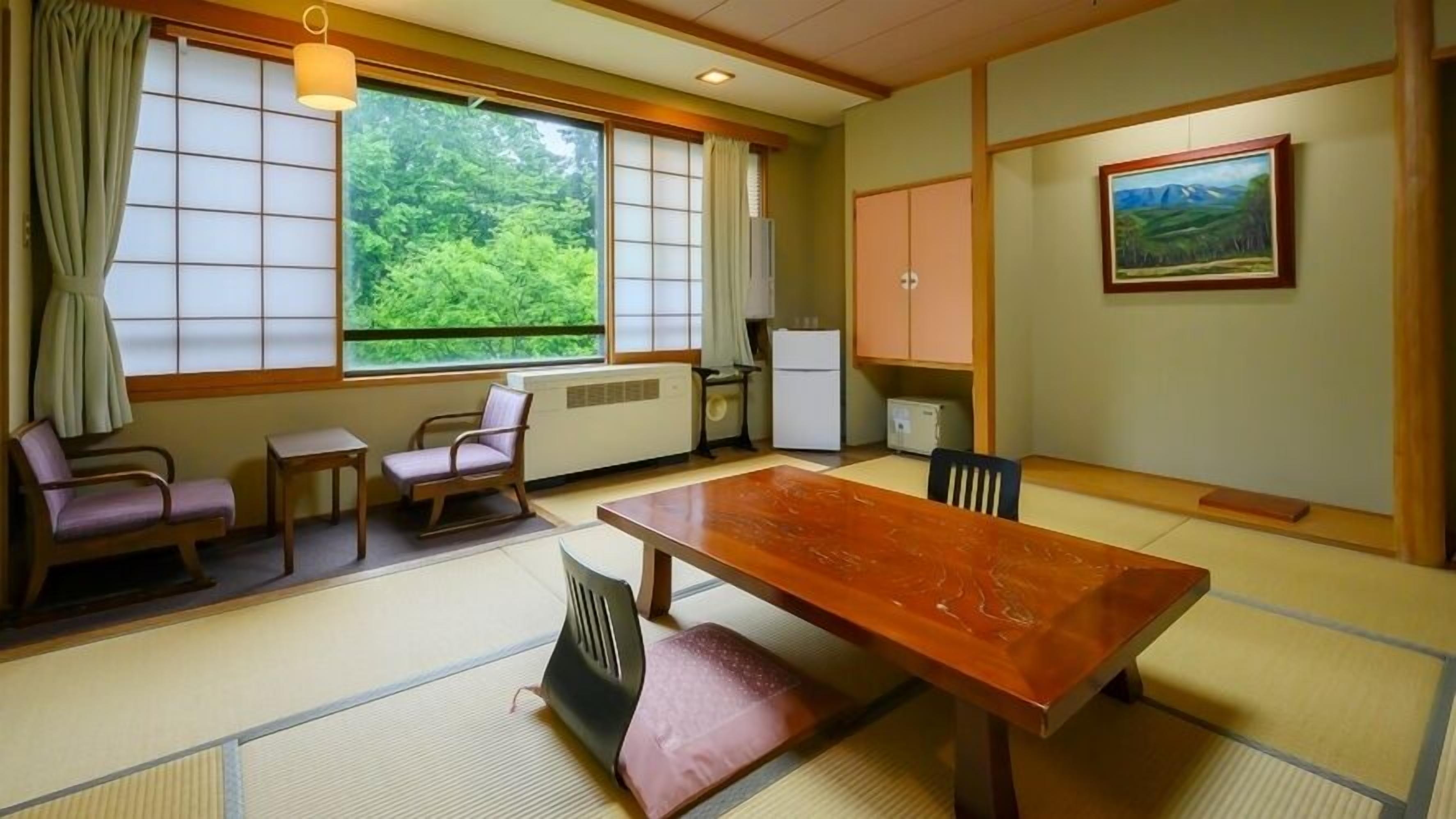 A traditional Japanese-style room with tatami flooring, a low table, and a view of greenery outside.