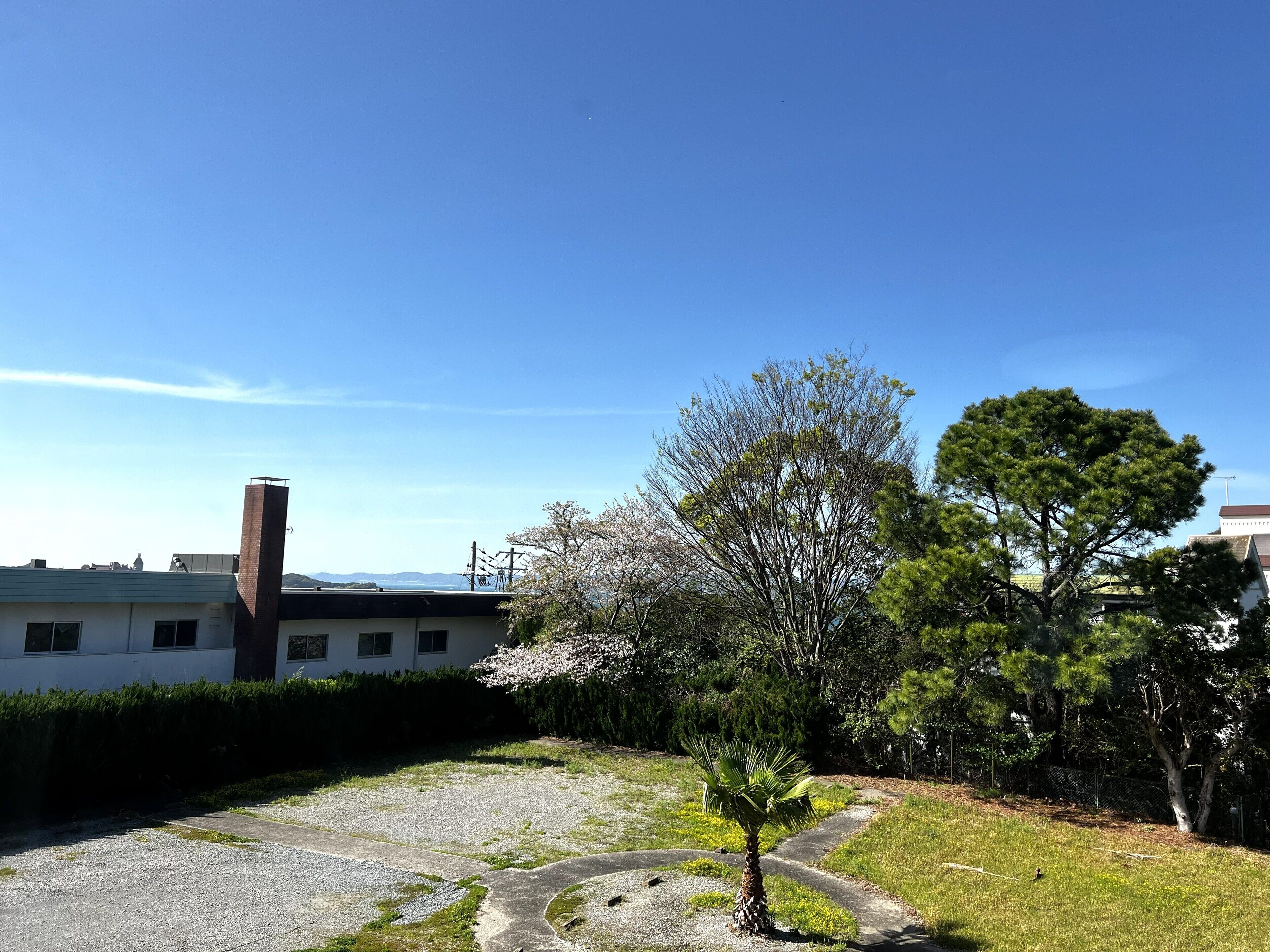 A building with a brick chimney, a gravel path, and a small tree in the foreground.