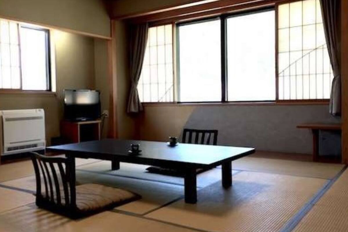A traditional Japanese room with tatami flooring, a low table, and a television.