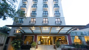 A hotel entrance with a covered walkway, steps leading up to the entrance, and potted plants.