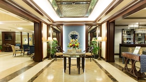 A lobby with a central table, chairs, and a reception desk.