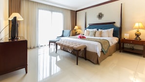 A hotel room with a large bed, a chair, a desk, and a television.