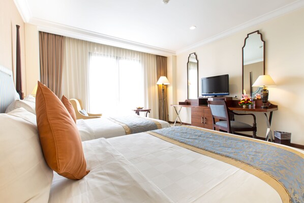 Habitación de hotel con dos camas, un escritorio con televisor y un espejo grande.