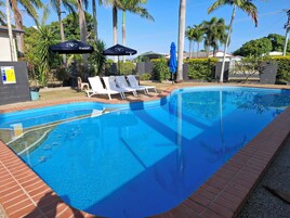 Una piscina al aire libre, sillones reclinables de piscina