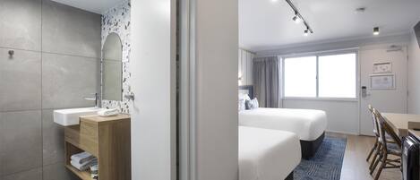 Una habitación de hotel moderna con baño, cama, escritorio y zona de comedor.